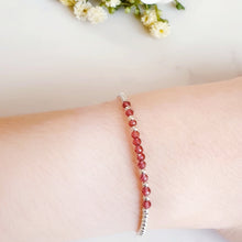 Load image into Gallery viewer, Faceted red garnet gemstone beads in the centre of a silver beaded bracelet