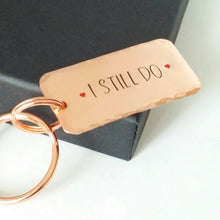 Load image into Gallery viewer, Copper keyring, hand stamped I STILL DO, with red hearts. 40mm x 20mm, textured around the edges. Large and small split rings.
