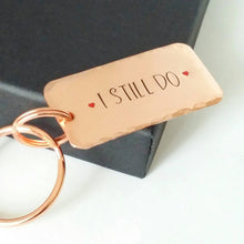 Load image into Gallery viewer, Copper keyring, hand stamped I STILL DO, with red hearts. 40mm x 20mm, textured around the edges. Large and small split rings.