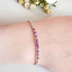 Purple Amethyst beads surrounded by silver beads in a bracelet