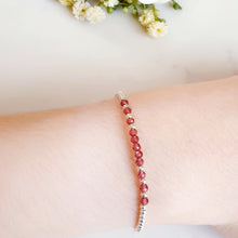 Load image into Gallery viewer, Faceted red garnet gemstone beads in the centre of a silver beaded bracelet

