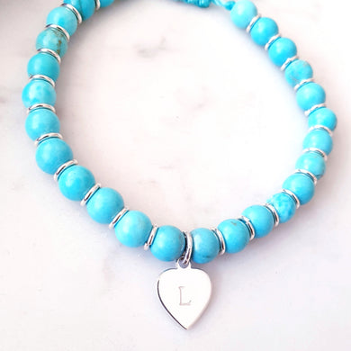 Blue beaded bracelet with rings in between each bead a personalised heart charm. Adjustable cord bracelet.