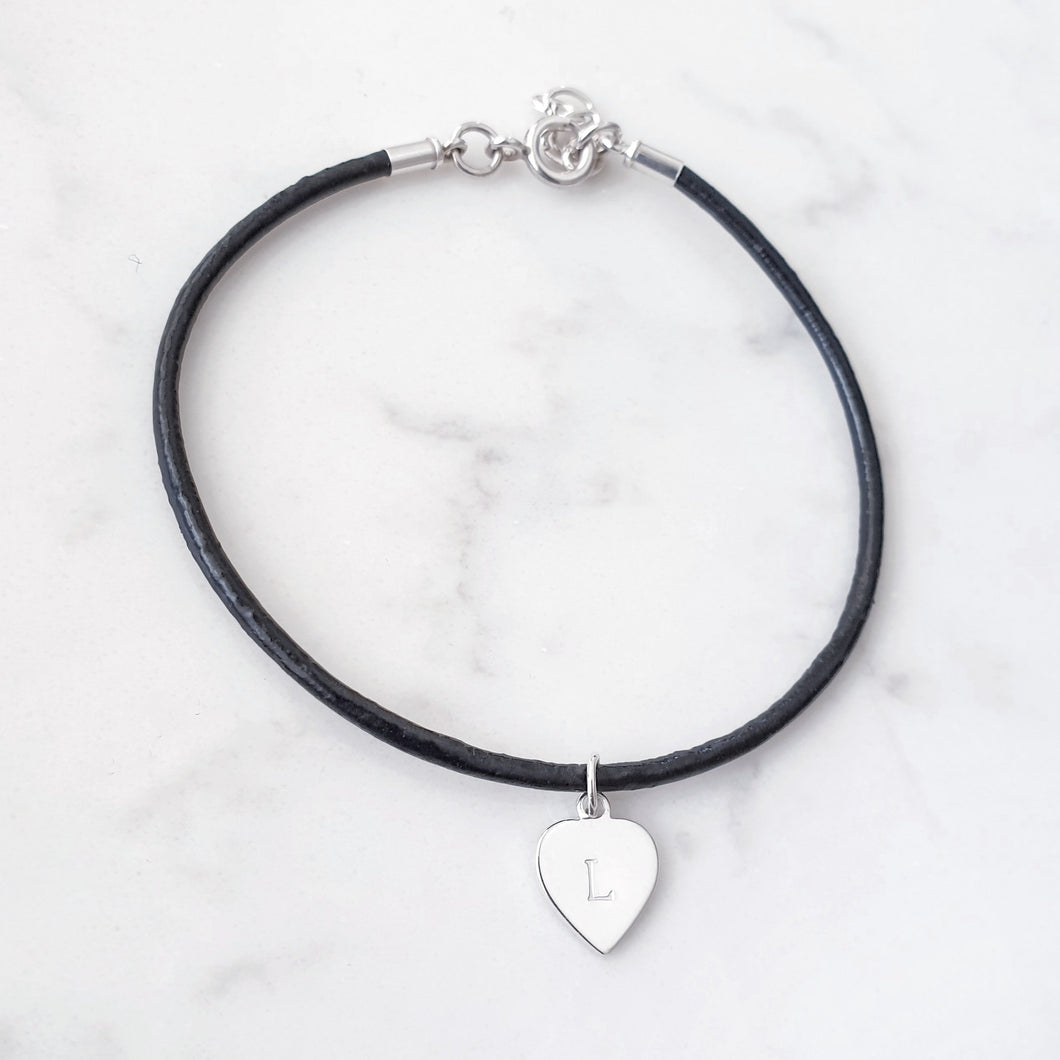 Black leather bracelet, 3mm thick with a sterling silver heart charm with an initial.  Bracelet has an extender